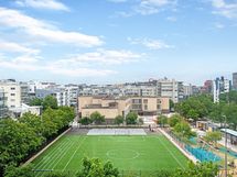 Näkymä makuuhuoneen ikkunasta. Jalkapallokentän takana ala-asteen koulu.