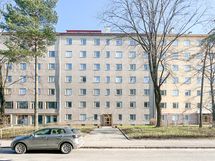 Taloyhtiö seisoo jykevästi omalla tontillaan.