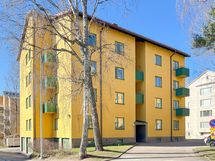 Taloyhtiö seisoo jykevästi omalla tontillaan.
