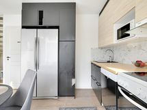 Keittiössä täyskorkea jääkaappi sekä pakastin.