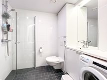 Vaalea kylpyhuone, jossa liitäntä edestä täytettävälle pyykinpesukoneelle.