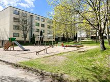 Pihalla on lasten leikkitelineitä ja istuinryhmiä.