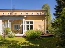 Suojaisalla pihalla on lasitettu terassialue, aurinkoterassi, istutuksia ja nurmikkoa.