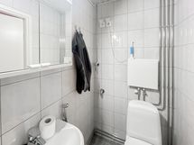 Laatoitettu kylpyhuone, jossa wc, suihku ja pesukoneliitäntä.