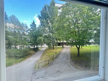 Näkymä keittiöstä ja makuuhuoneesta taloyhtiön etupihalle.