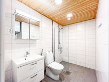 Kylpyhuone on laatoitettu. Allaskaappi ja peilikaappi tarjoavat säilytystilaa.