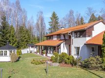 Aurinkoinen piha huvimajalla. Paljon istutuksia