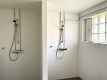 Taloyhtiön saunatilan suihkuhuone, jossa kaksi suihkua.
