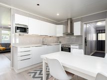 Keittiö. Taustalla käytävä, jossa sijaitsee kylpyhuone, sauna, tekninen tila ja kulku terassille.