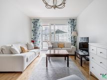 Valoisa olohuone, josta käynti lasitetulle parvekkeelle sisäpihan puolelle.