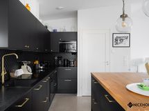 Upea tumma keittiö laadukkaine kodinkoneineen.