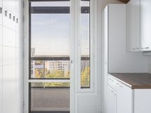 Kodinhoitohuone -tila ja käynti lasitetulle parvekkeelle.