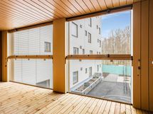 Valokuva asunnosta B 32 - näkymä lasitetulta parvekkeelta korttelipihalle.