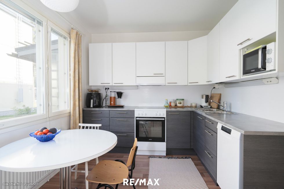 Tyylikäs keittiö, jossa on riittävästi kaappeja ja kokkaustilaa