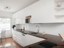 Tyylikäs keittiö, jonka perällä on tila pienemmälle ruokailuryhmälle.