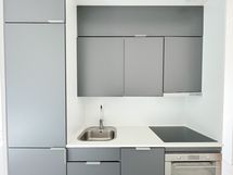 Tyylikkäässä avokeittiössä on induktioliesi ja astinapesukone.