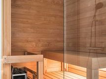 Valokuva asunnosta B 41 - Saunan lauteet ovat tervaleppää, ovi ja seinä kirkasta lasia.