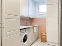 Tilavassa kylpyhuoneessa on käytönnöllinen kodinhoitohuonenurkkaus, jossa on pesukone valmiina.