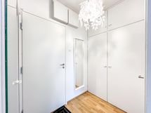 Eteisessä hyllylliset kaapit. Vastapäätä naulakko sekä siivouskaappi.