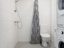 Täysin laatoitettu kylpyhuone jossa suihku ja wc.