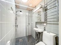 Siistikuntoiseen ja kokonaan laatoitettuun kylpyhuoneeseen mahtuu kapeanmallinen pyykinpesukone.