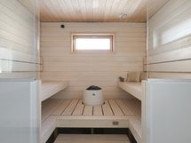 Vaaleasävyinen sauna lasiseinällä.