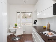 Tyylikäs keittiö, jonka perällä on tila pienemmälle ruokailuryhmälle.