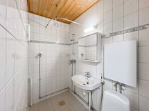 Laatoitettu kylpyhuone, jossa wc, suihku ja pesukoneliitäntä.
