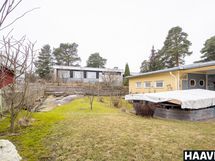 Pihapiirin istutuksia, kalliota ja terassi peitteen alla