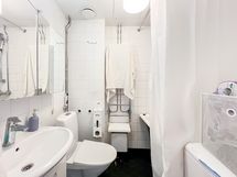 Kylpyhuone on täysin laatoitettu. Oven vieressä paikka ylhäältä täytettävälle pyykinpesukoneelle.