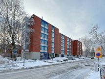 Taloyhtiö seisoo jykevästi omalla tontillaan.