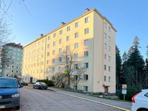 Taloyhtiö seisoo jykevästi omalla tontillaan.