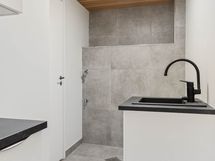 Kodinhoitohuone sijaitsee kellarikerroksessa. Tilaa on niin pyykinpesukoneelle kuin kuvausrummulle kätevästi vierekkäin sijoitettuna.