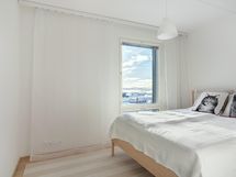 Makuuhuoneen ikkunasta pilkottaa meri.