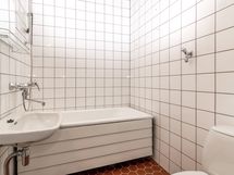 Kylpyhuone on kaakeloitu vaaleilla kaakeleilla.Sieltä löytyy amme, wc-istuin, käsiallas ja peili.