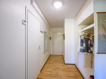 Näkymää keittiön suunnalta ulko-ovelle, vasemmalla ovi johtaa kylpyhuoneeseen ja oikealla eteisen vaatesäilytys.