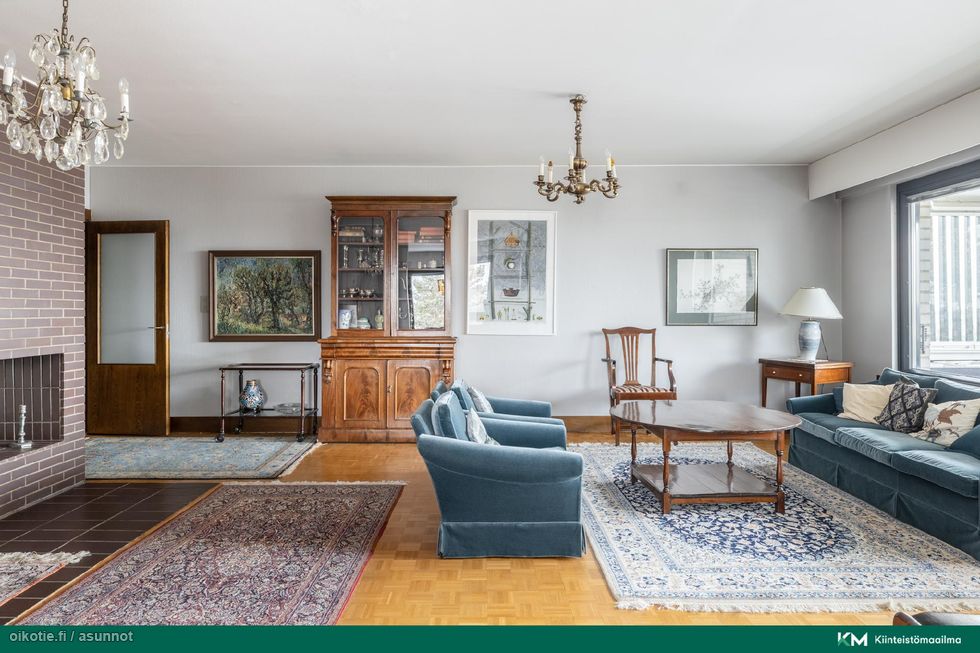 Avara ja elegantti olohuone, jossa takka ja kauniit materiaalit korostavat tämän hyvin hoidetun kodin laatua ja viihtyisyyttä