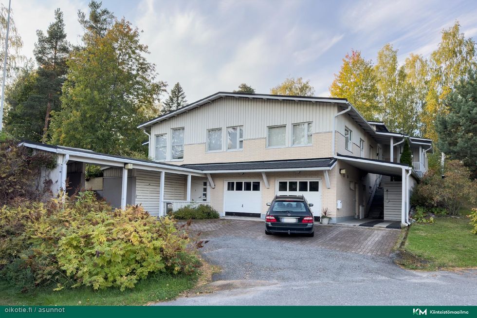 Julkisivu kadultapäin. Edessä autokatos, myytävän huoneiston autotalli vasemmalla puolella