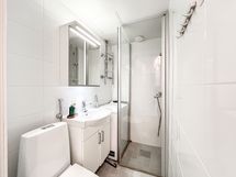 Kylpyhuone on täysin laatoitettu ja valmiina käytössä pyykinpesukone.