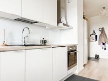 Vaaleassa keittiössä reilusti säilytys- sekä laskutilaa ja integroitu astianpesukone.