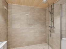 Kauniin hiekan sävyisessä kylpyhuoneessa on paikka omalle pesukoneelle, Taloyhtiössä myös ilmainen pesula!