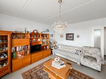 Olohuoneessa on kirjahyllykkö ja sohvakalusto.