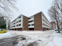 Taloyhtiö seisoo jykevästi omalla tontillaan.