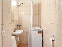 Kylpyhuoneessa pyykinpesukone valmiina.