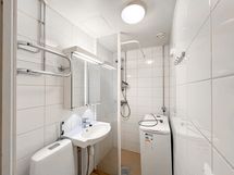 Laatoitettu mukavan kokoinen kylpyhuone, jossa hyvä suihkutila ja pesukone valmiina asukkaalle.