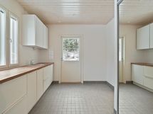 Kodinhoitohuone on tilava tasoineen ja kaapistoineen.