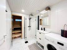 Kaunis saunallinen kylpyhuone, jossa pyykinpesukoneelle paikkansa.